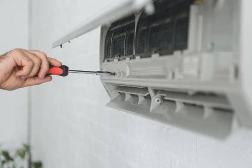 partial view of male worker repairing air conditioner with screw